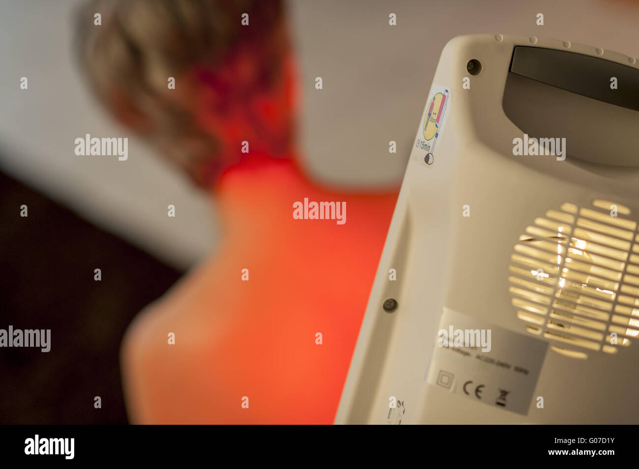 Una donna si siede con la schiena contro una luce rossa Foto Stock