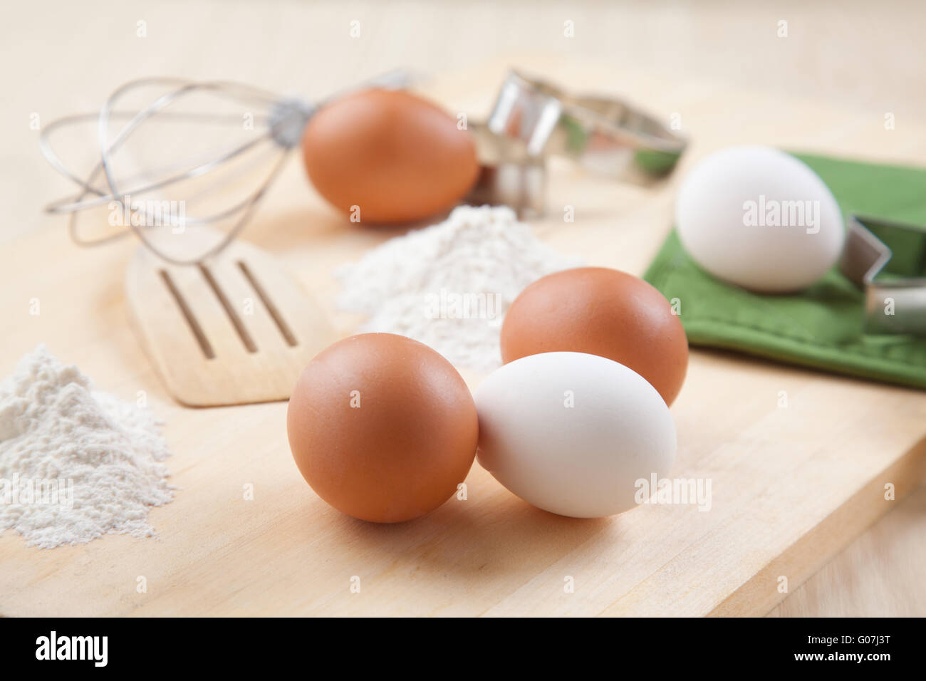Le uova, la farina e mescolare con una frusta sulla tavola di legno insieme Foto Stock