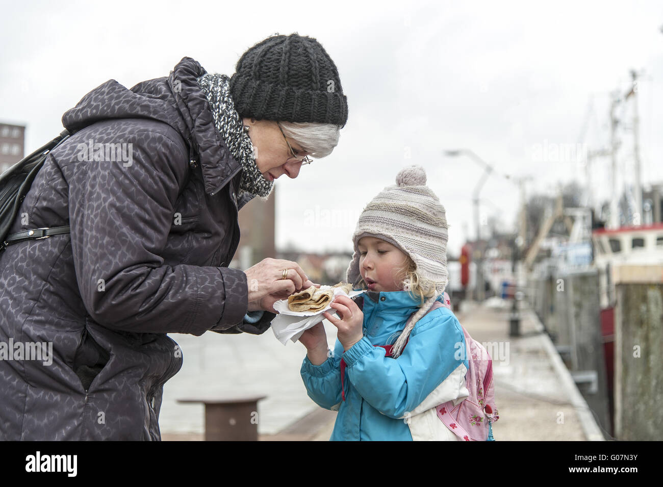 Una nonna aiuta il suo nipote mentre mangia Foto Stock
