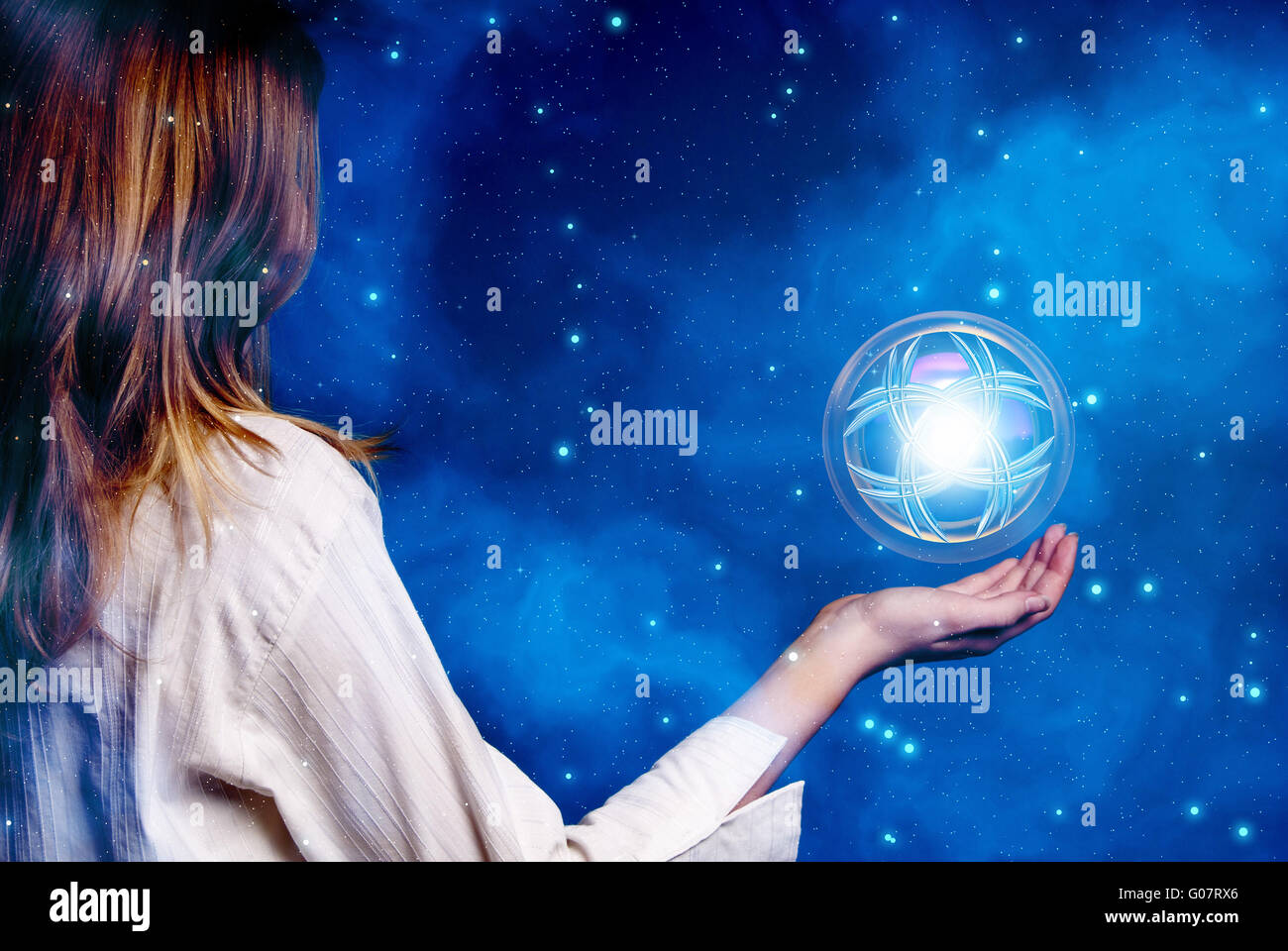 Donna in maglia bianca con una sfera magica in bilico in mano Foto Stock