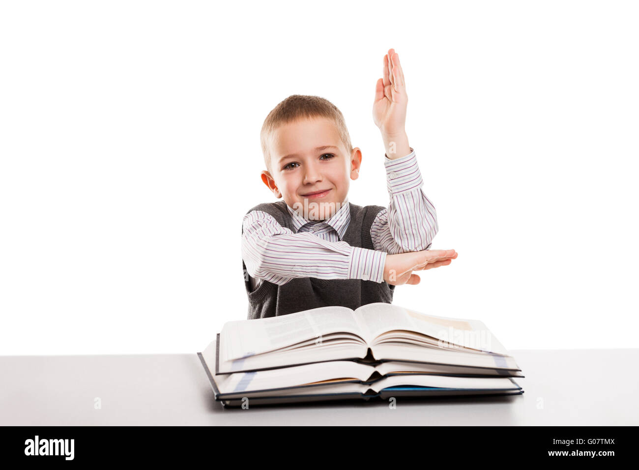Bambino con libri al desk gesticolando mano fino ad ans Foto Stock