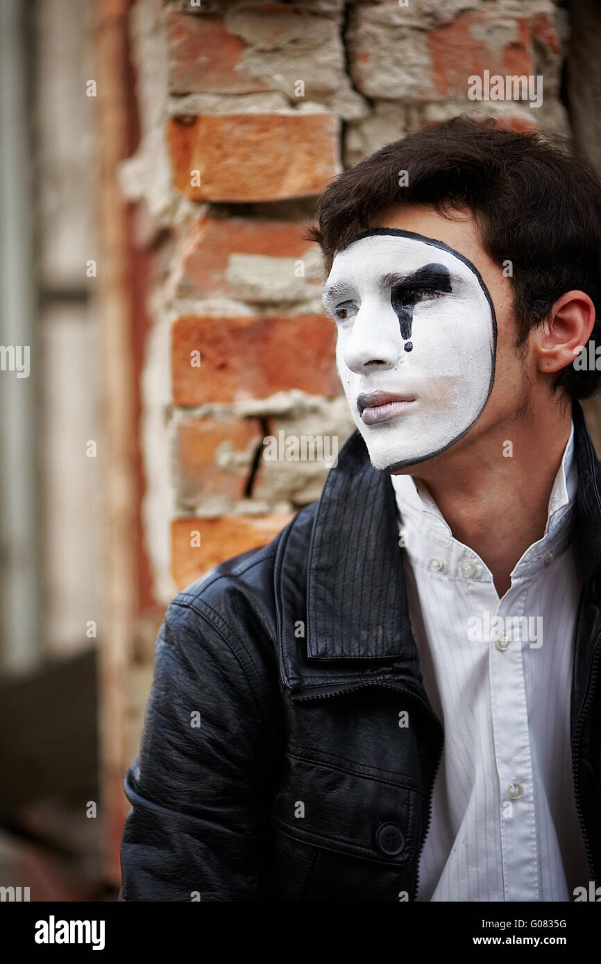 Guy mime contro un vecchio muro di mattoni. Foto Stock