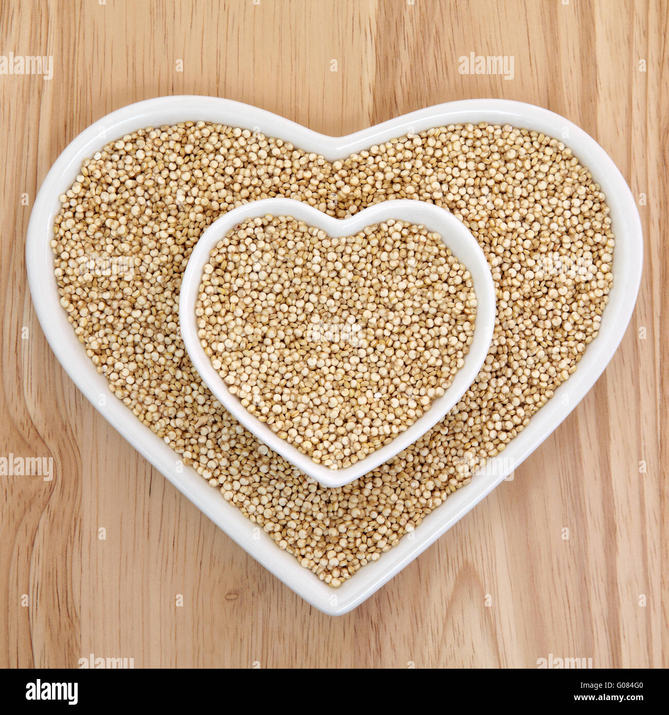 La quinoa grano della salute alimentare nel cuore a forma di piatti di porcellana con legno di faggio sfondo. La Salvia hispanica. Foto Stock