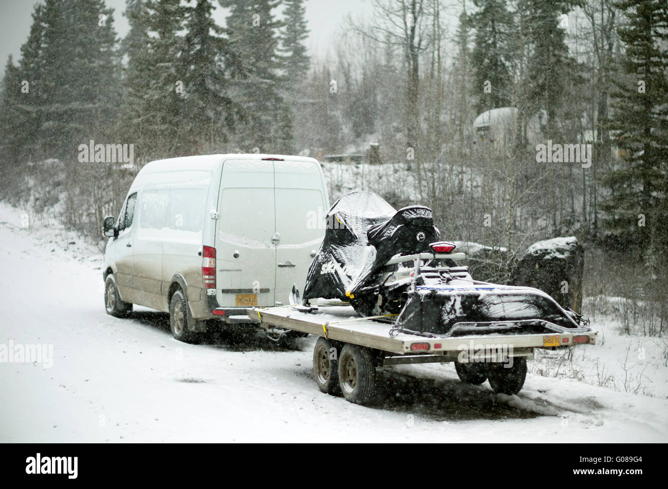 Guida invernale in Alaska. Freightliner Sprinter Cargo furgone tirando la Ski Doo Spedizione macchina neve sul rimorchio alla fine Foto Stock