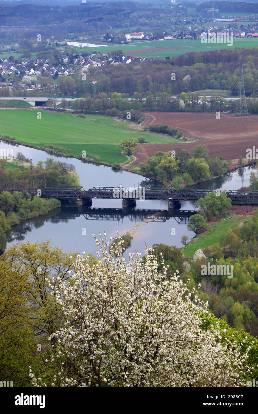 Ponte che attraversa un fiume a valle verde e terreni agricoli Foto Stock