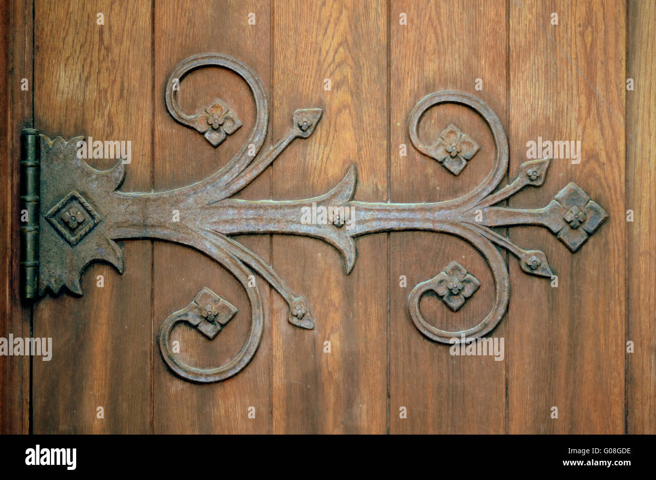 Close-up di un ferro da stiro ornamentali a cerniera su una vecchia porta di legno Foto Stock