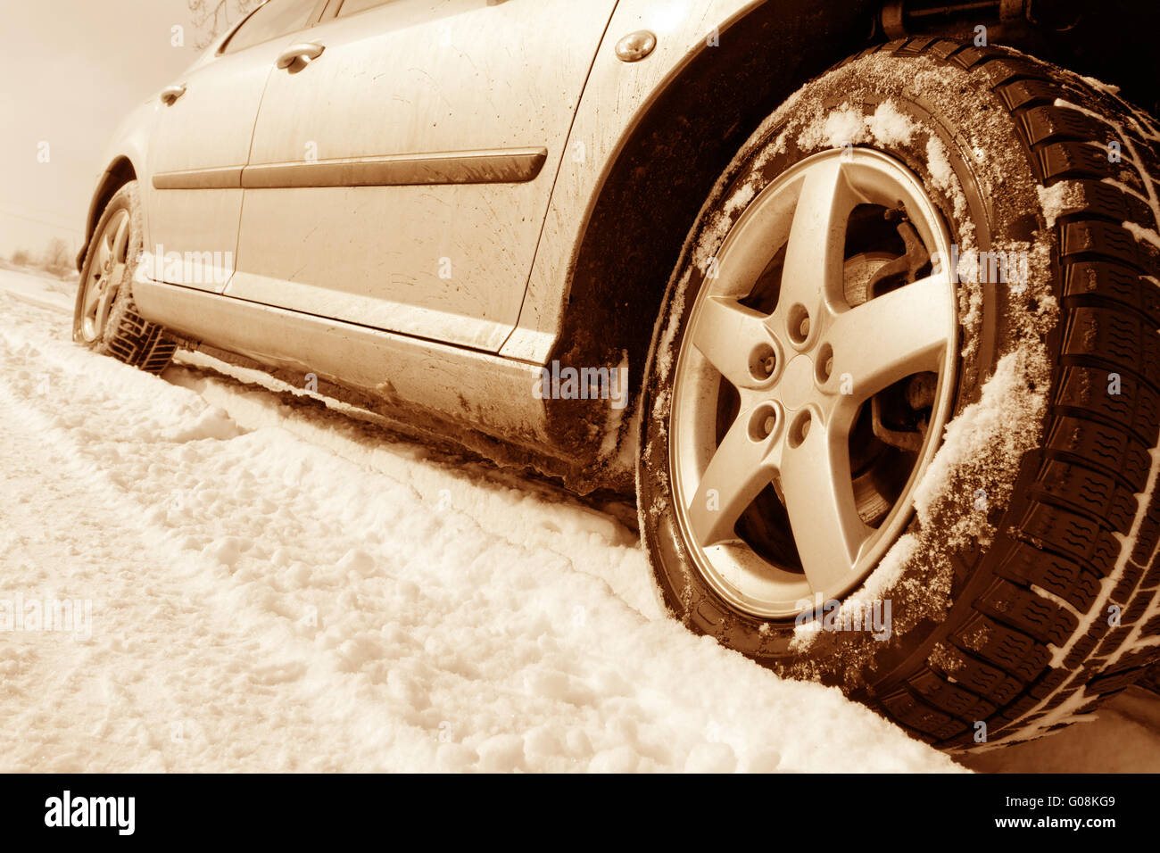 Close up di un auto pneumatici su una strada innevata - tonalità seppia Foto Stock