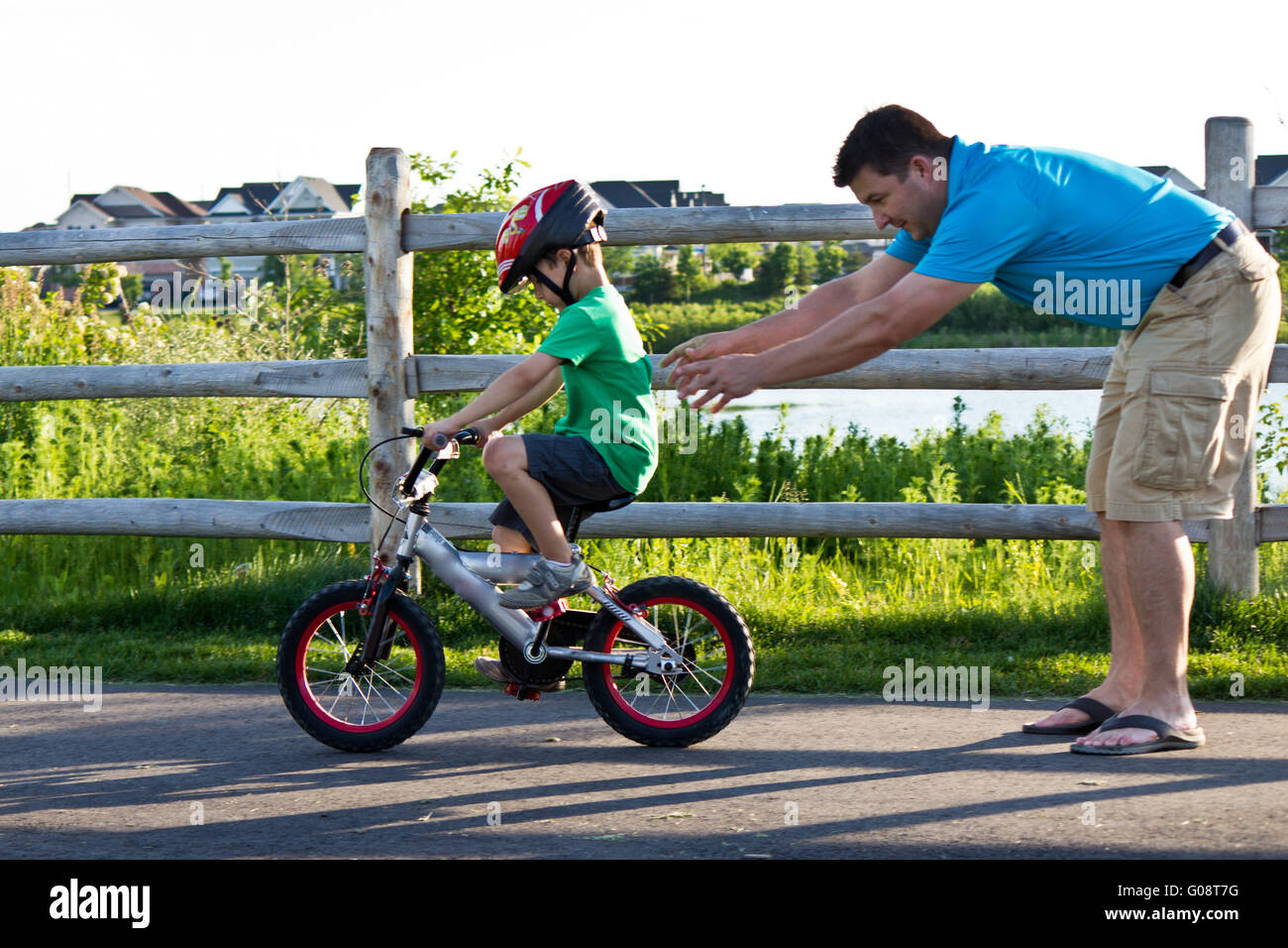 Bambino imparare ad andare in bicicletta con il padre Foto Stock