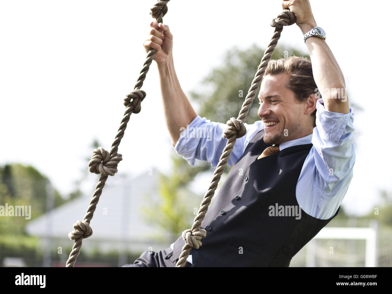 Happy businessman giocando, oscillanti in funi Foto Stock