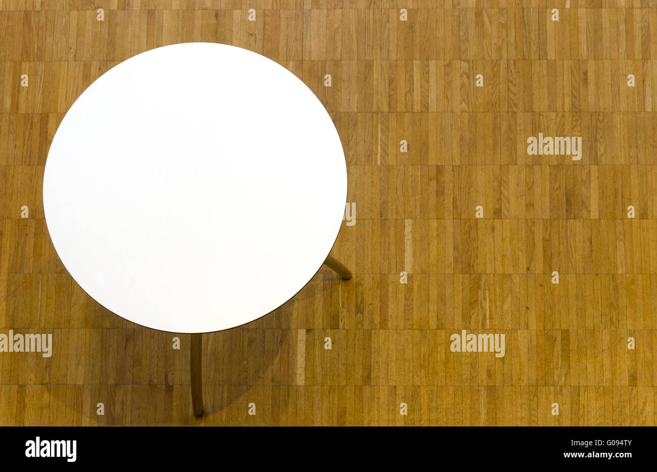 Tavolo circolare con top bianco e pavimento in parquet Foto Stock