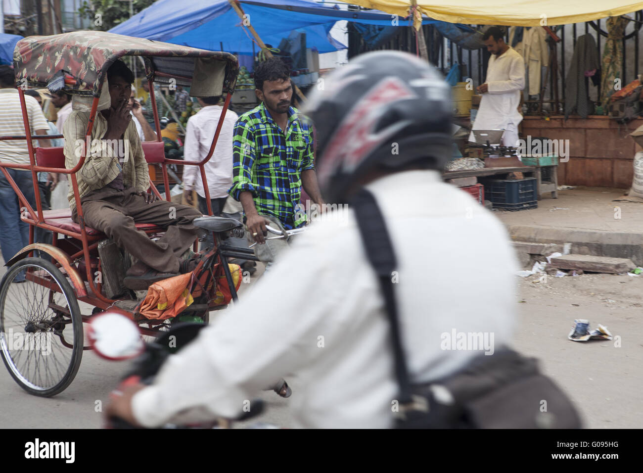 Conducente di un motociclo attraversare un rickshaw, Dehli Foto Stock