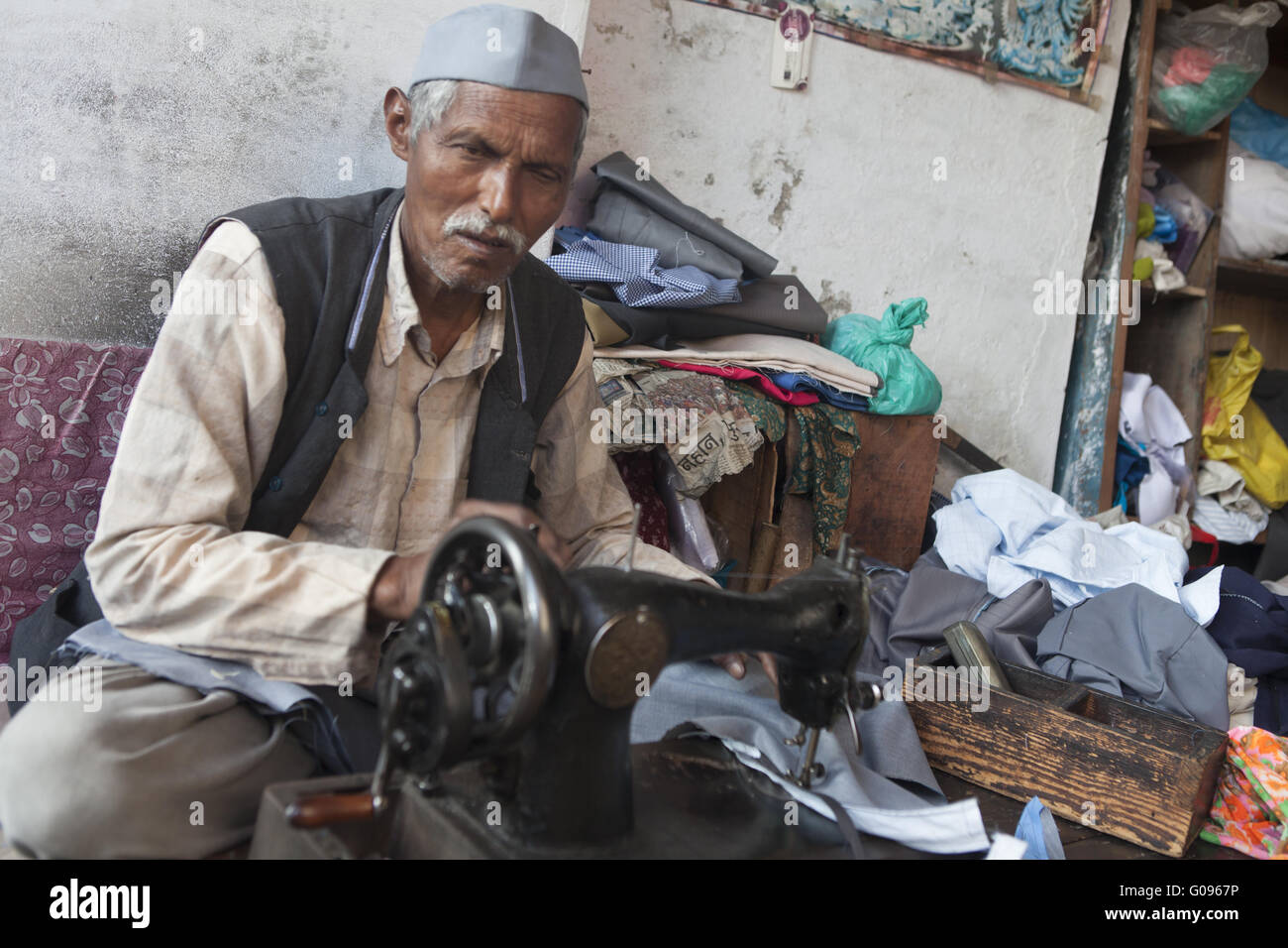 Sarto rendendo i vestiti su una vecchia macchina da cucire, India Foto Stock