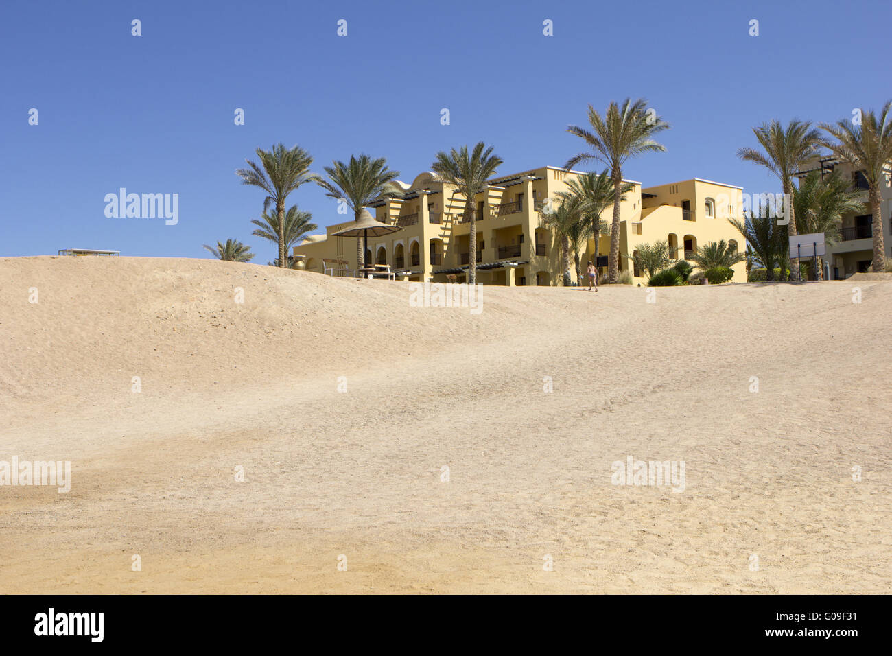 Edificio alla fine di un deserto con palme Foto Stock