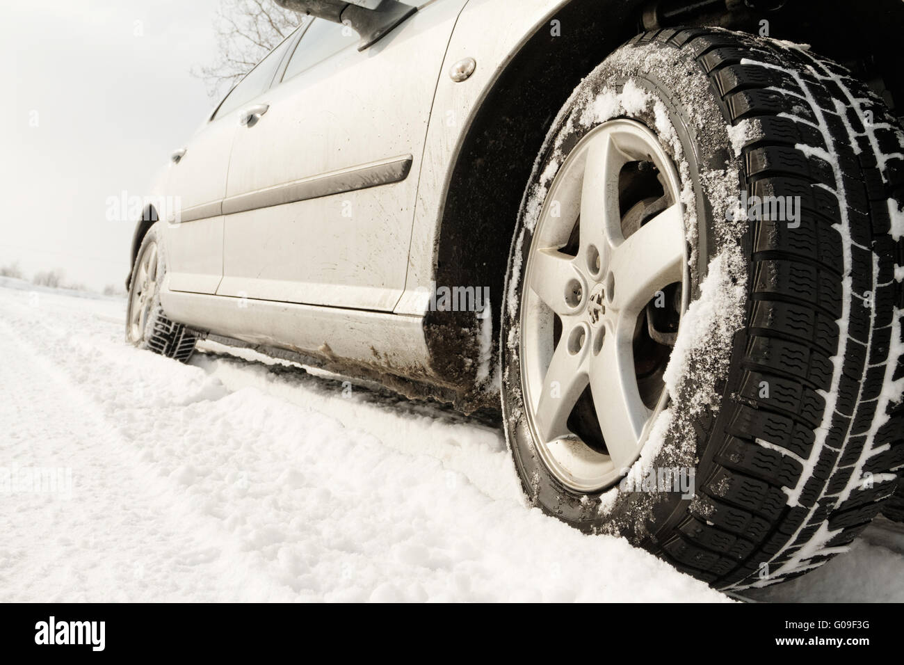 Close up di un auto pneumatici su una strada innevata - tonalità seppia Foto Stock