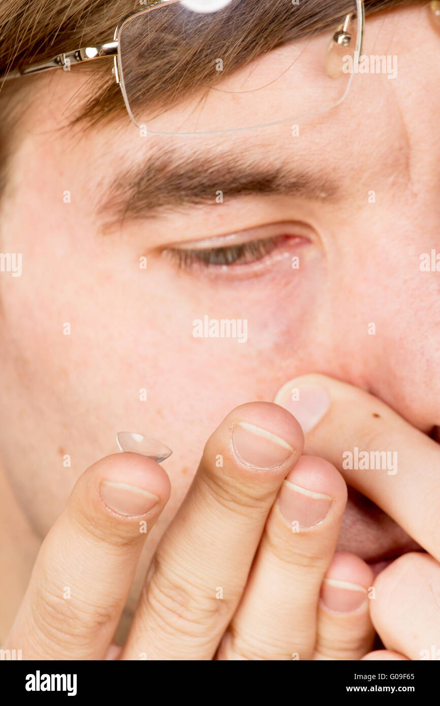 Primo piano di un uomo occhio marrone mentre inserendo un correttivo lente a contatto su un dito. Foto Stock