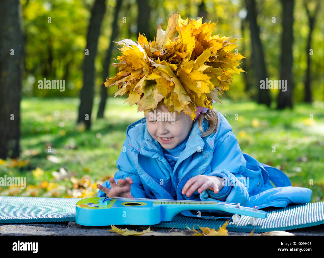 Bambina con un cappello giallo di foglie di autunno Foto Stock