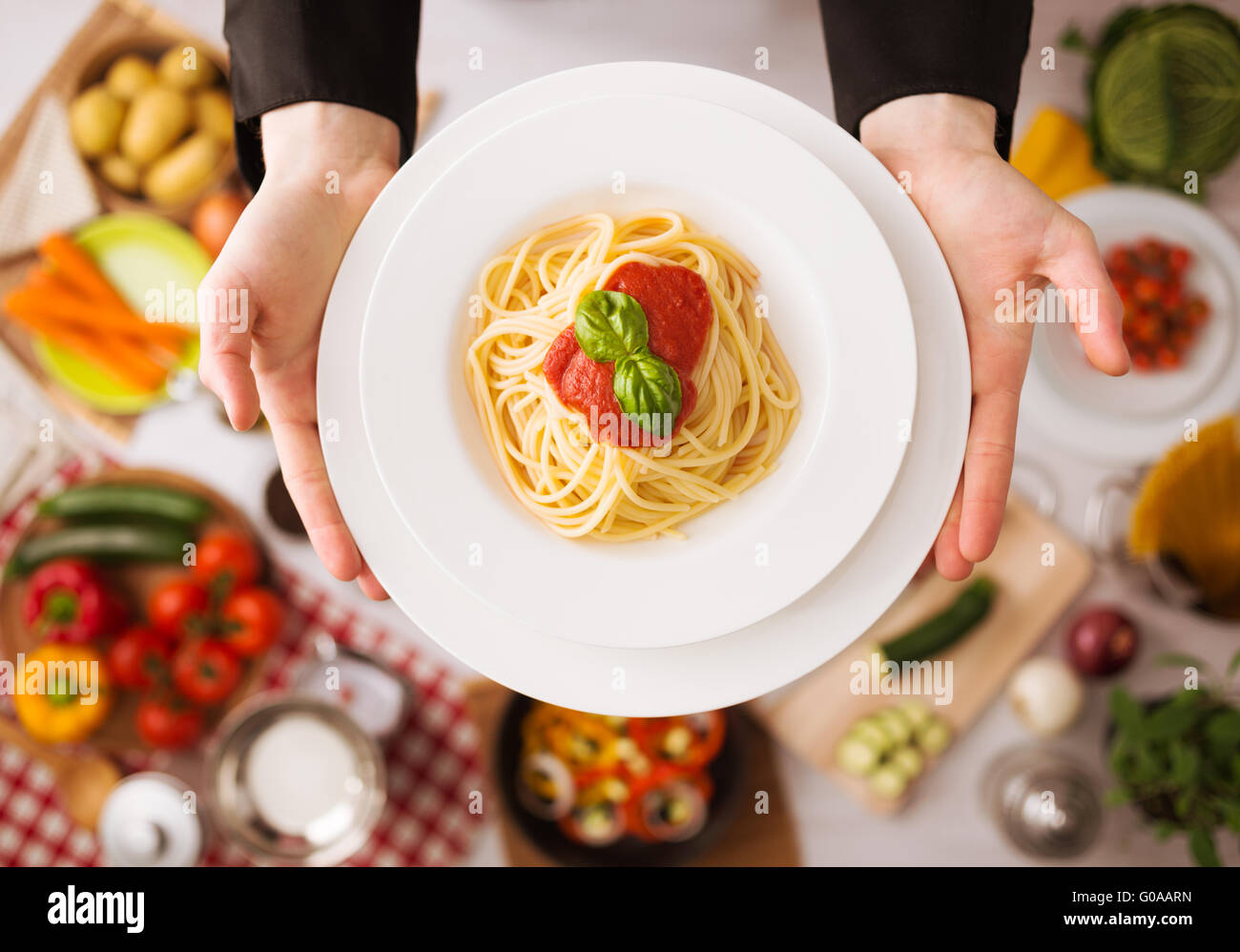 Chef professionale con le mani in mano la cottura della pasta su un piano di lavoro in legno con verdure, degli ingredienti alimentari e utensili, vista dall'alto Foto Stock