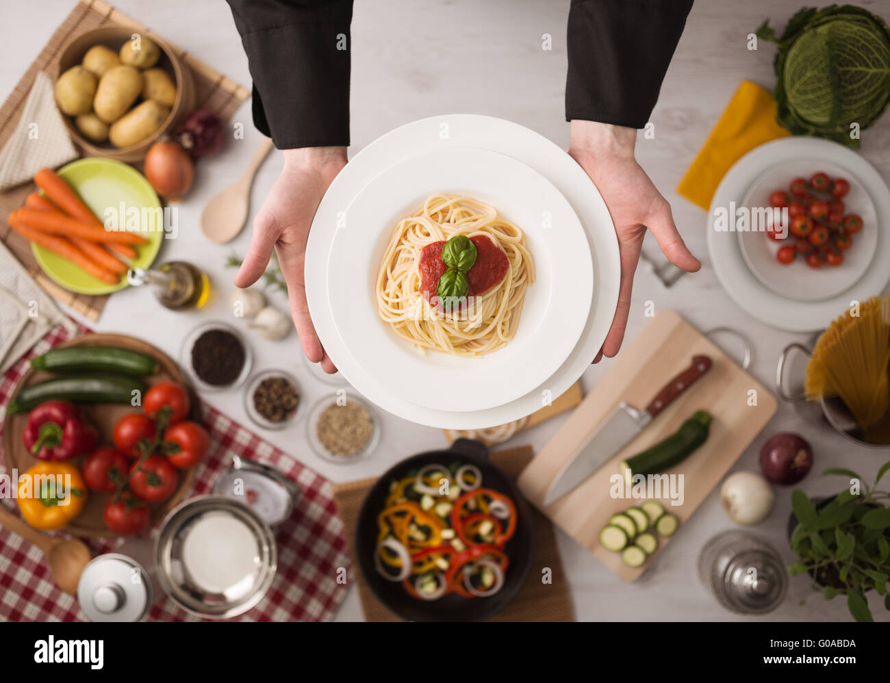 Chef professionale con le mani in mano la cottura della pasta su un piano di lavoro in legno con verdure, degli ingredienti alimentari e utensili, vista dall'alto Foto Stock