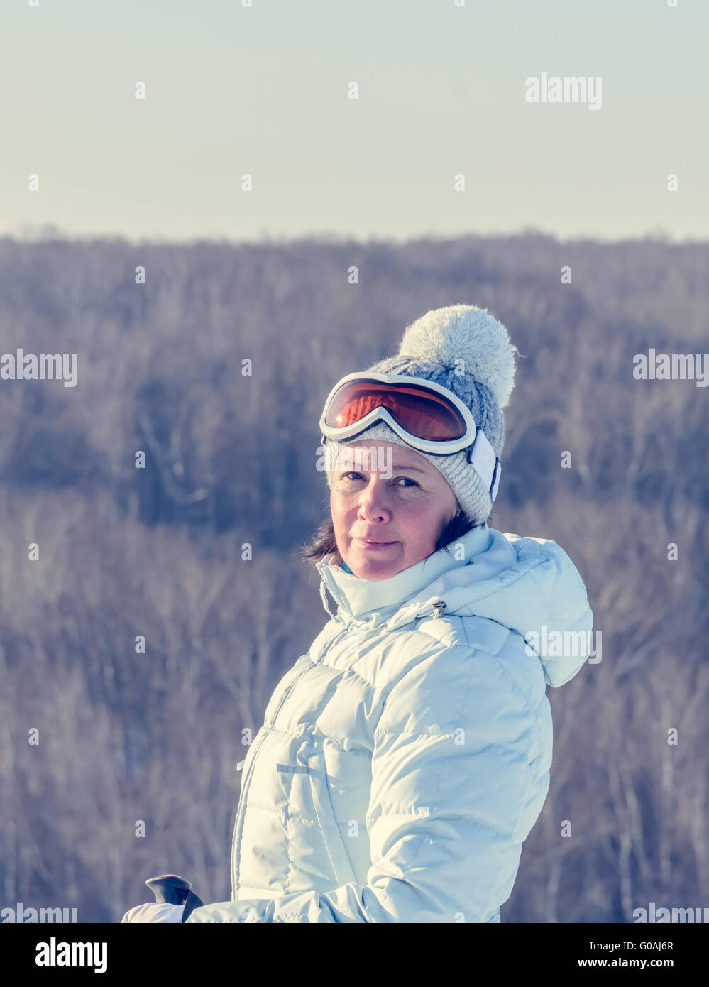 Di mezza età brunette sul pendio di una collina in un cappello e occhiali da sci Foto Stock