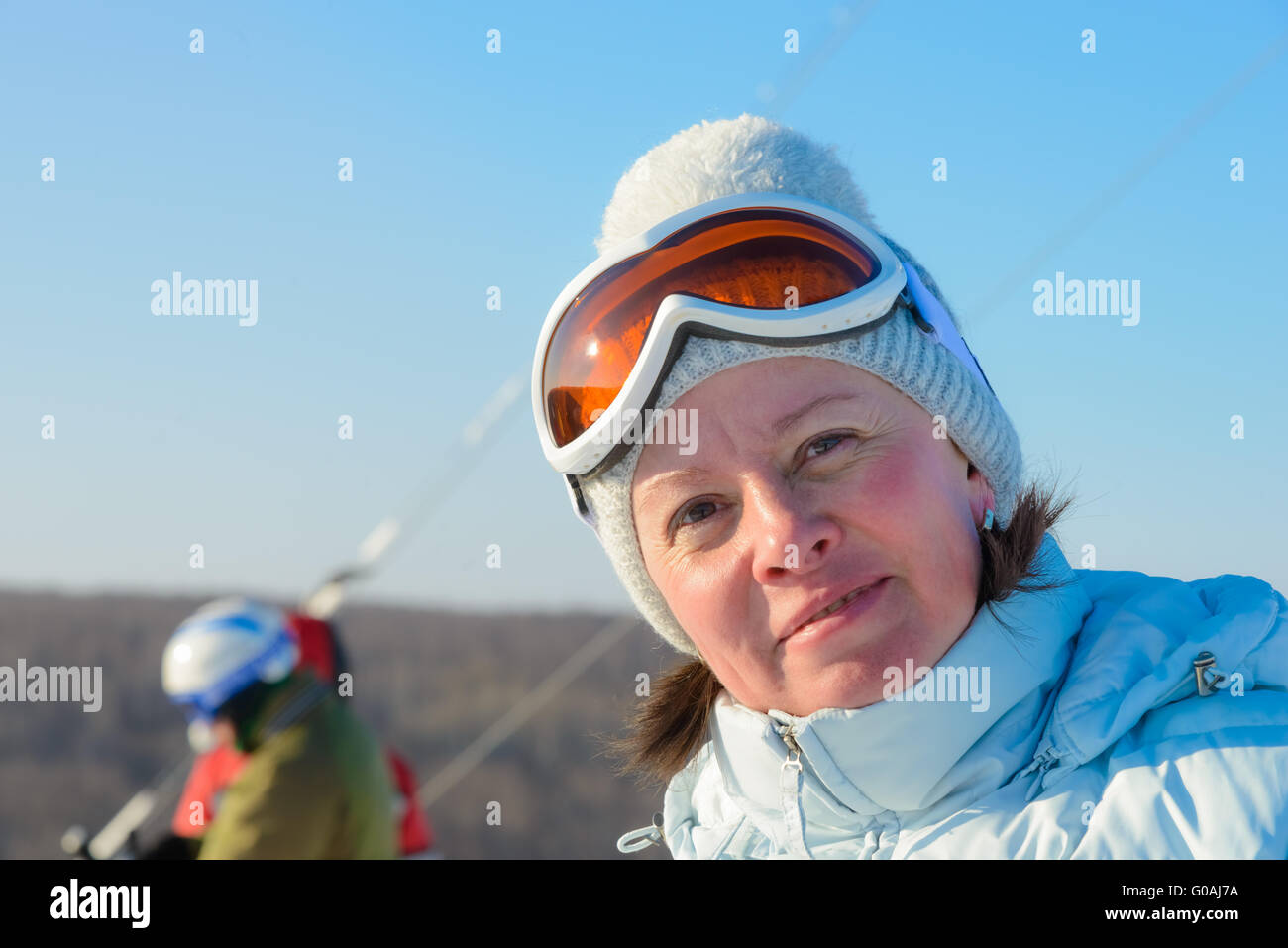 Di mezza età brunette sul pendio di una collina in un cappello e occhiali da sci Foto Stock