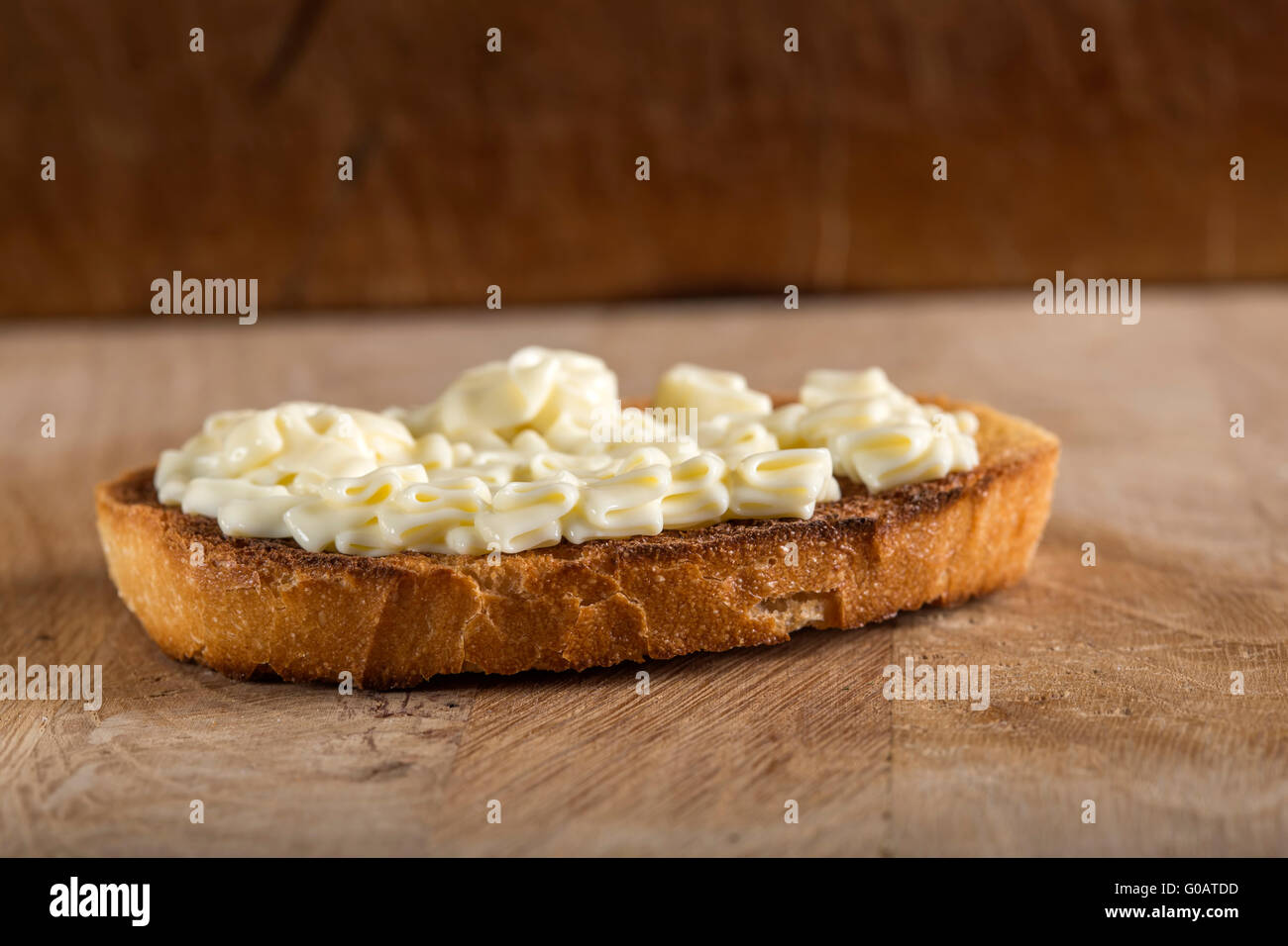 Formaggio fuso la crema sul pane tostato su sfondo di legno Foto Stock