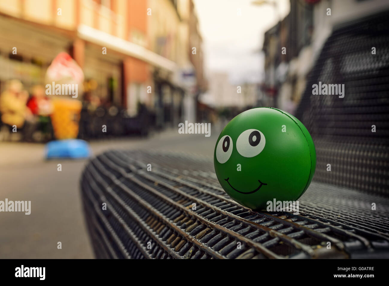 Green palla di gomma con una faccia sorridente sul banco di lavoro Foto Stock