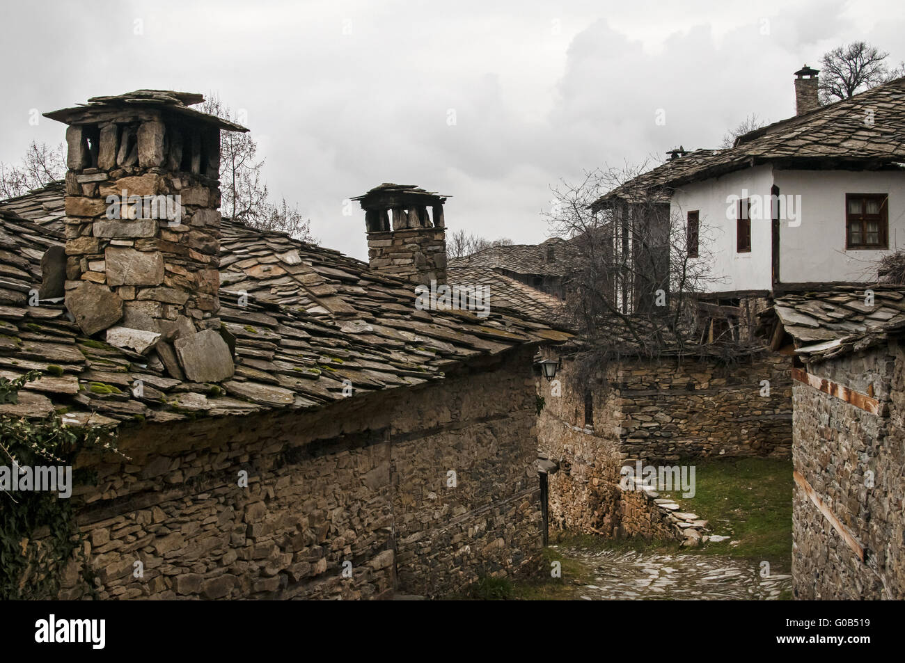 Vecchie piastrelle di pietra slide-tetto e stonewall rural hou Foto Stock