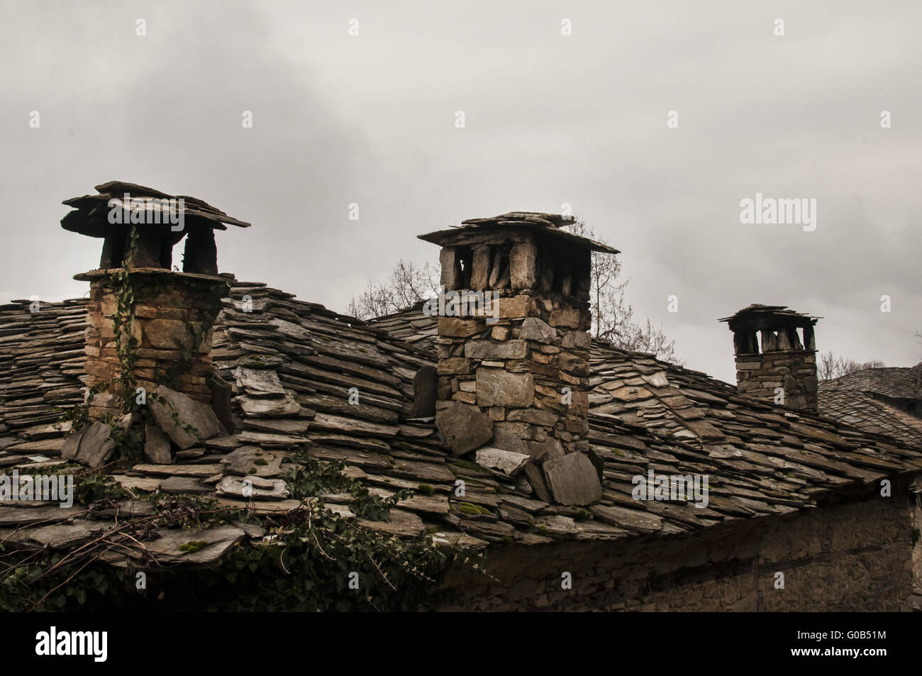 Vecchie piastrelle di pietra slide-tetto e stonewall rural hou Foto Stock