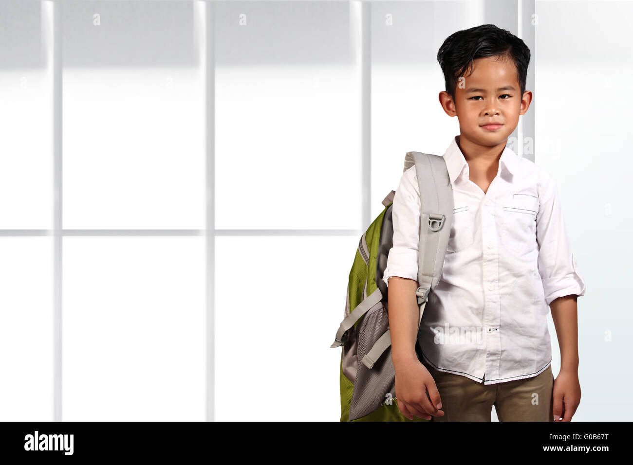 Giovane ragazzo asiatico studente in piedi e sorridente su sfondo lucido Foto Stock