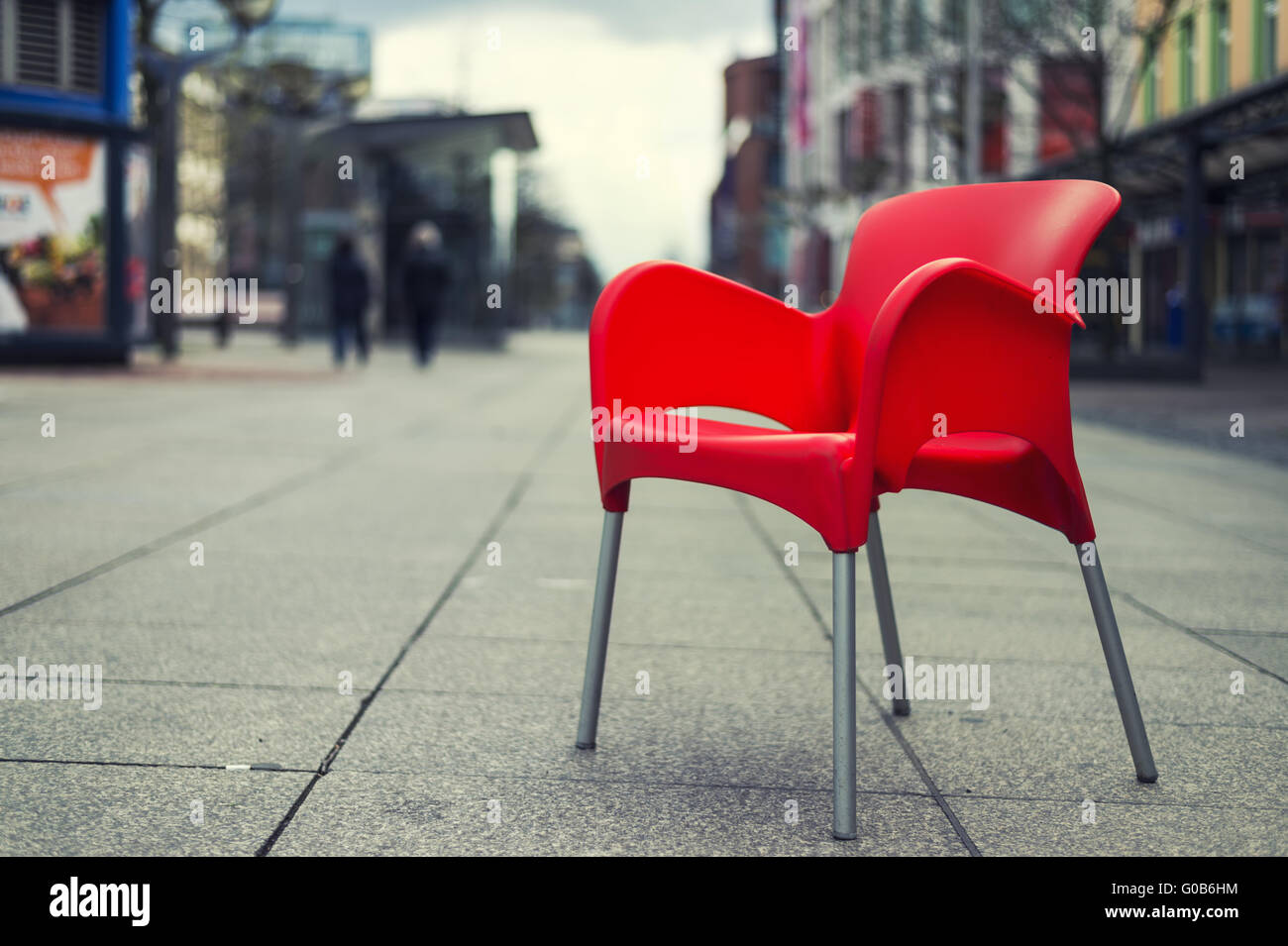 Una sedia rossa si siede su una strada vuota Foto Stock