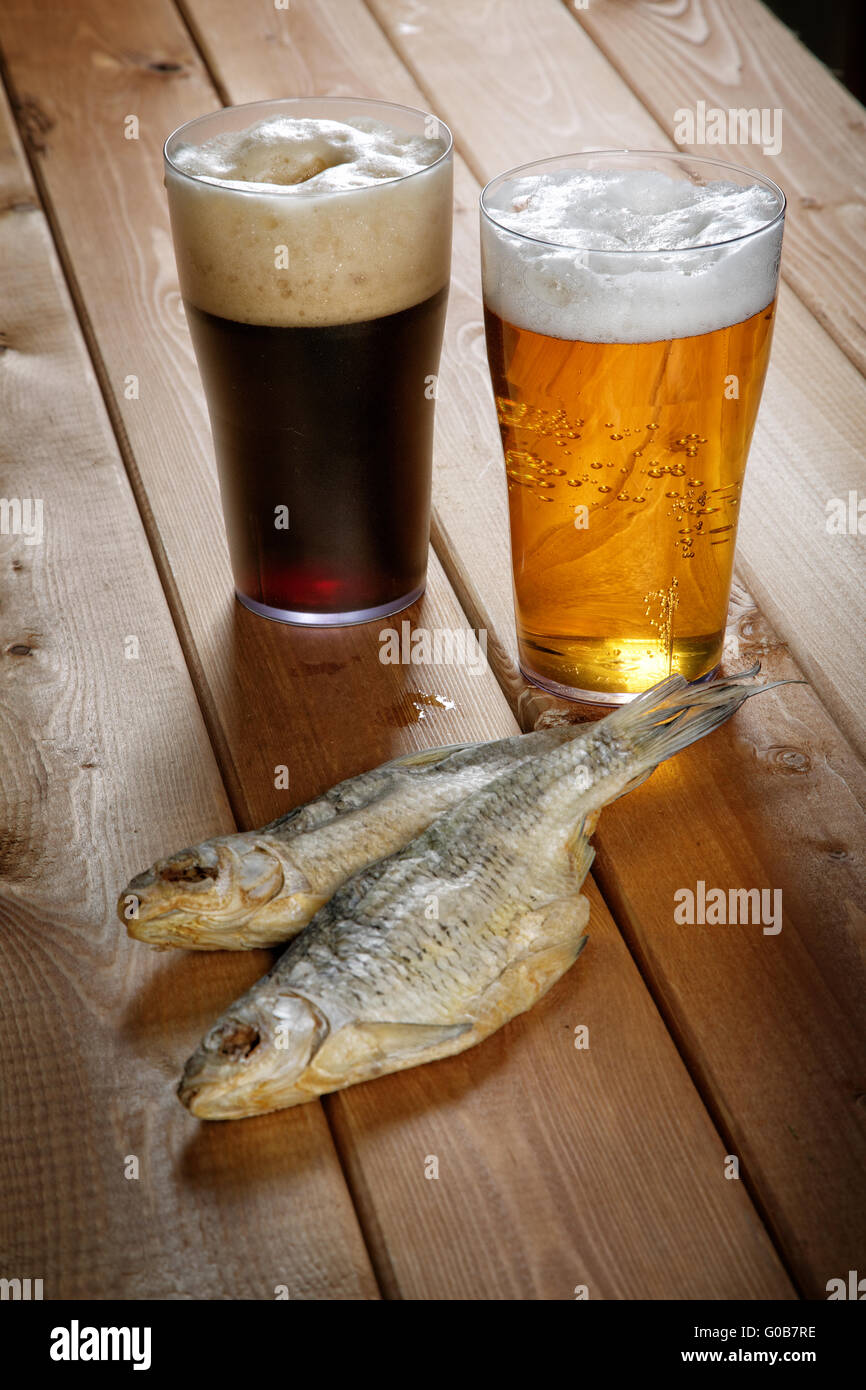 Due bicchieri di birra con pesci secchi su un tavolo Foto Stock