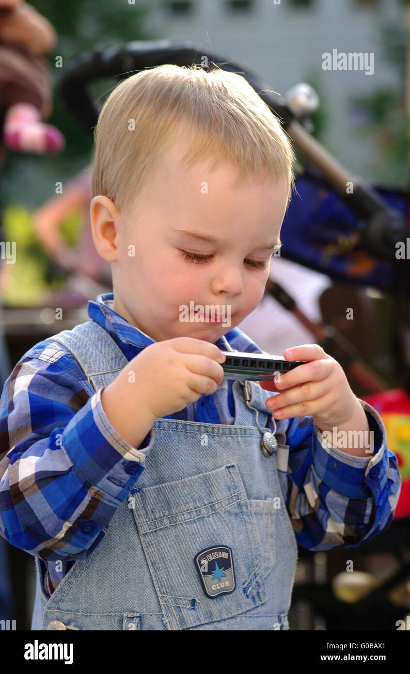 Piccolo Ragazzo esamina(indaga) una fisarmonica orale Foto Stock