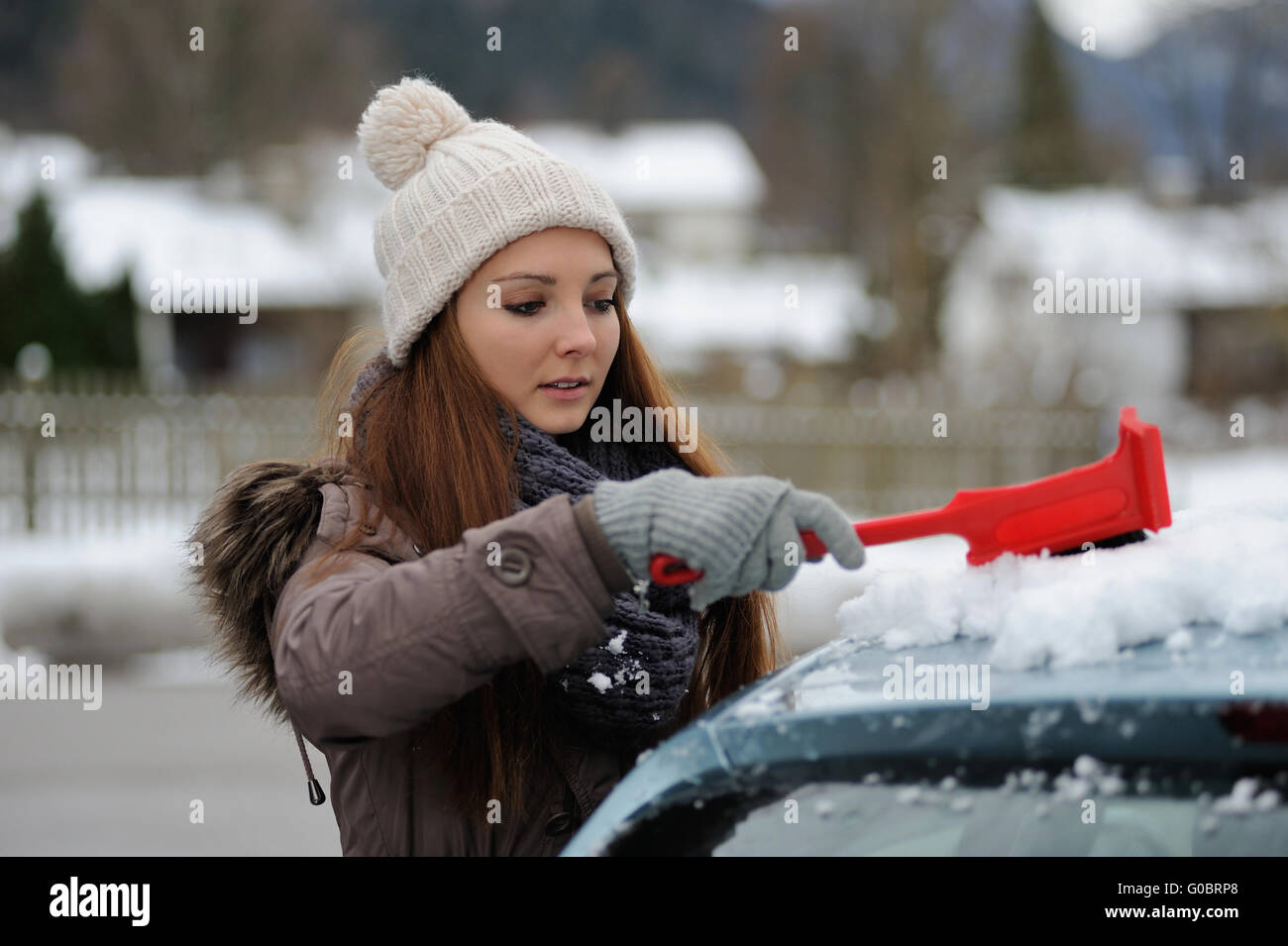 Giovani femmine spazza neve fuori la sua vettura Foto Stock