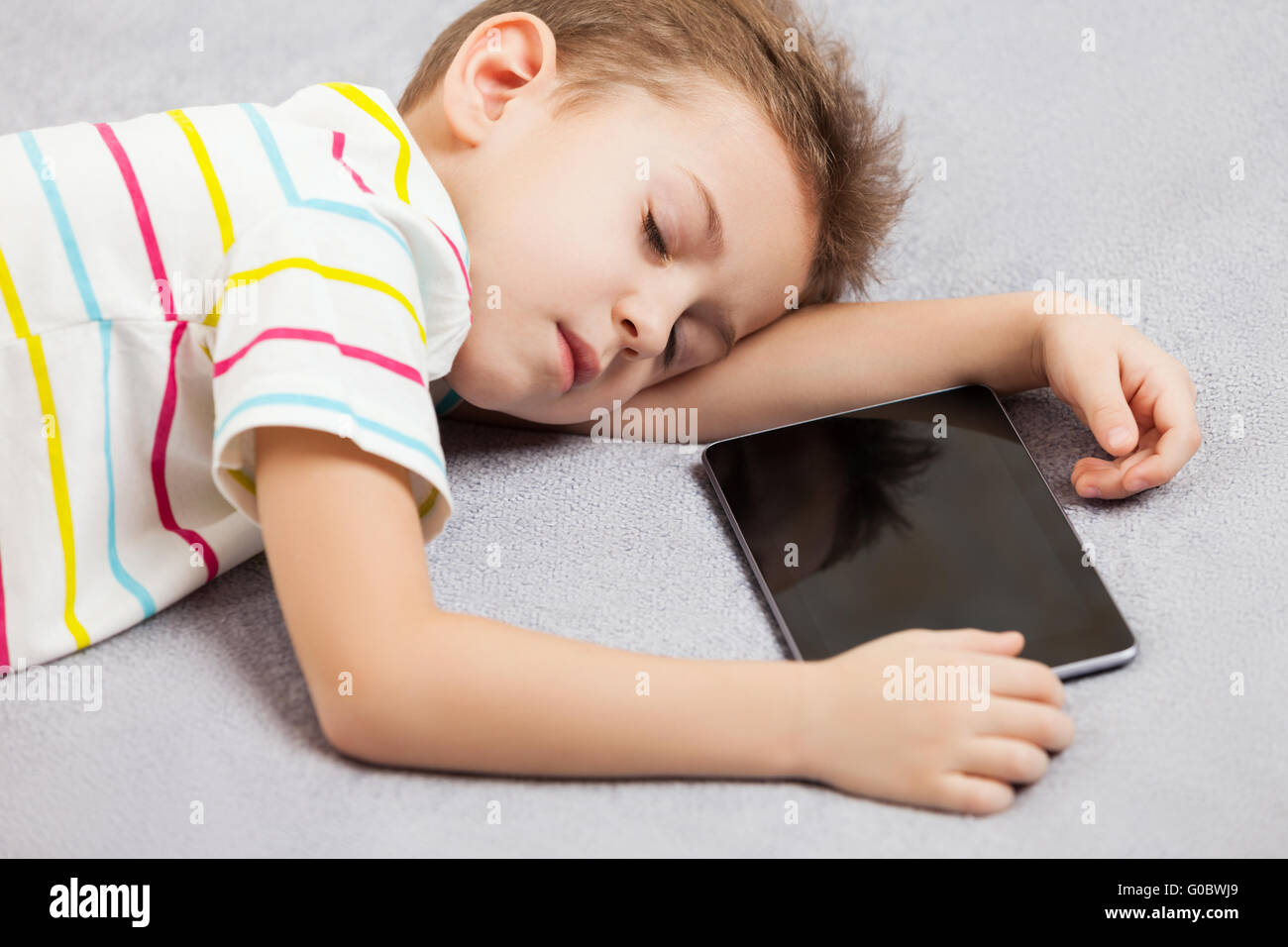 Stanco bambino dormiente boy holding computer tablet Foto Stock