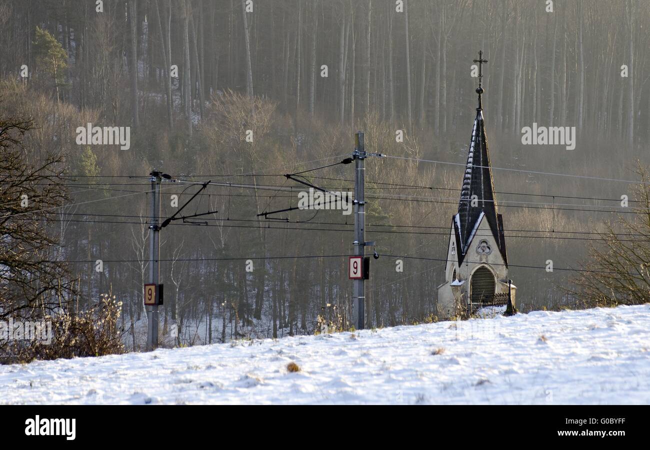 Guglia della chiesa dietro una ferrovia cablaggio tettuccio Foto Stock