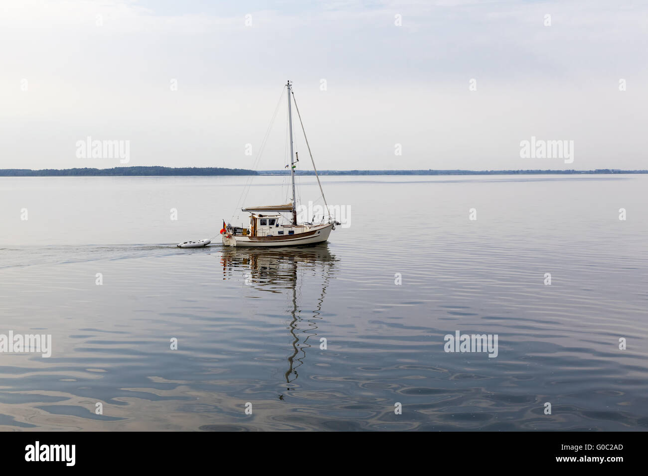 Piccola barca a vela con la riflessione sulla Bodden Foto Stock