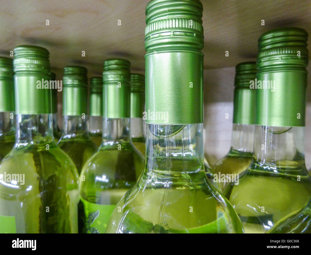 Le bottiglie di vino impilati su scaffalature in legno shot con limitata profondità di campo Foto Stock
