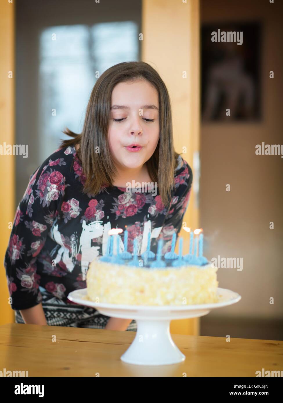 Ragazza come brucia candele su una torta di compleanno Foto Stock