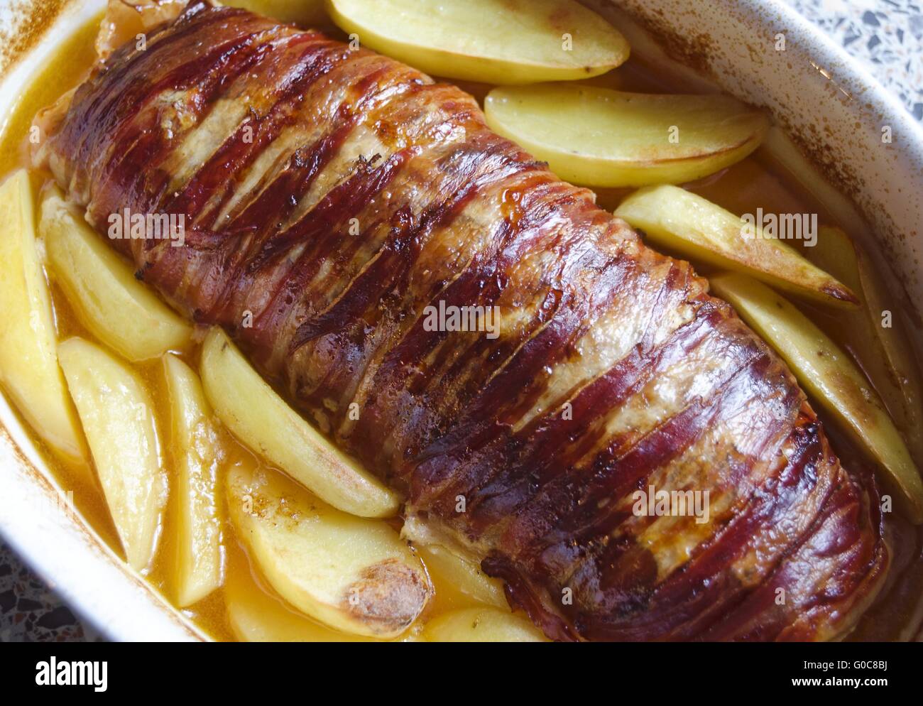 Patate fritte e metà arrosto avvolto da pancetta affumicata Foto Stock