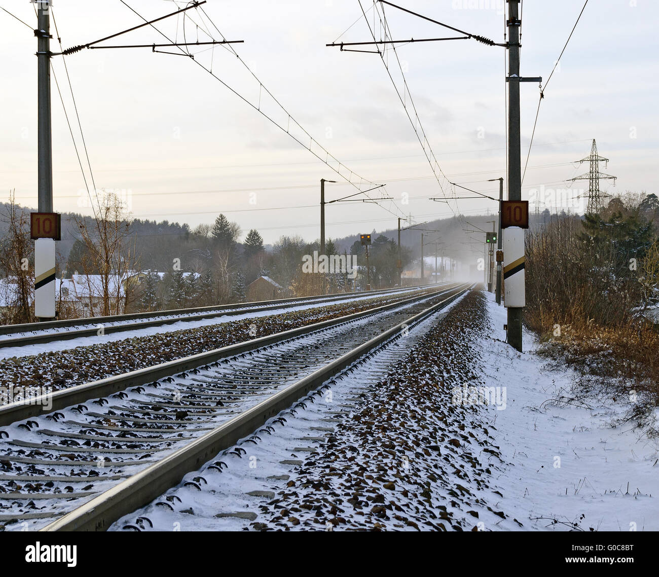 Snowy linea ferroviaria con sovraccarico elettrico cablaggio Foto Stock