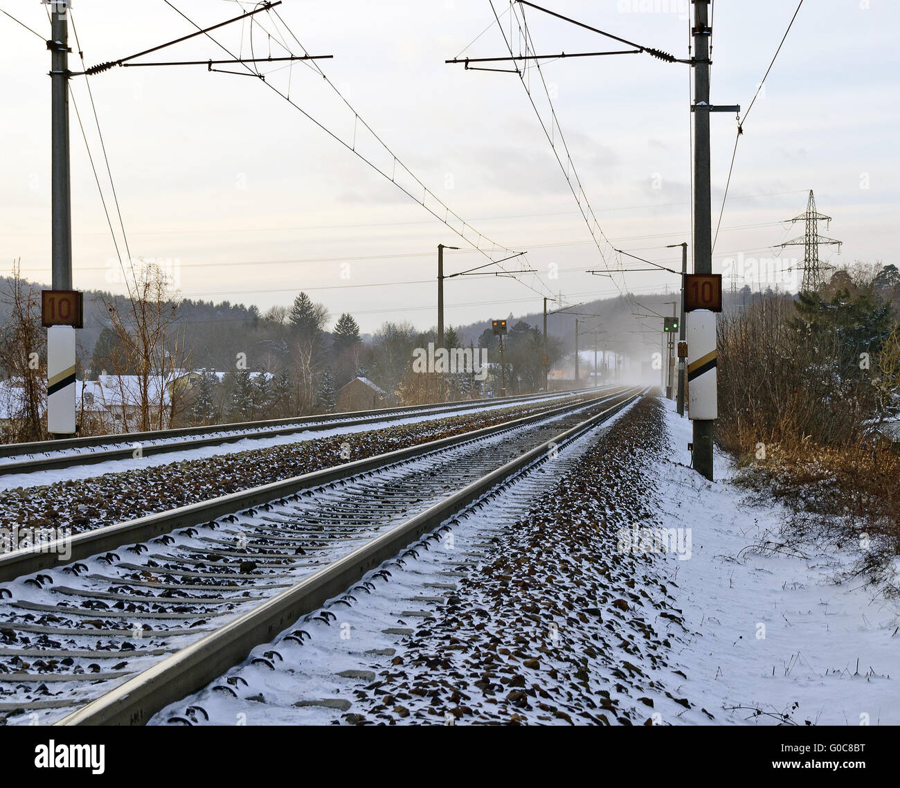 Snowy linea ferroviaria con sovraccarico elettrico cablaggio Foto Stock