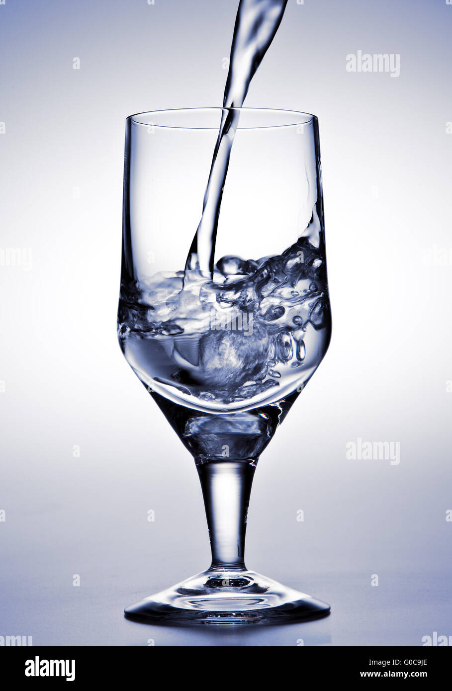 L'acqua viene versata in un bicchiere Foto Stock