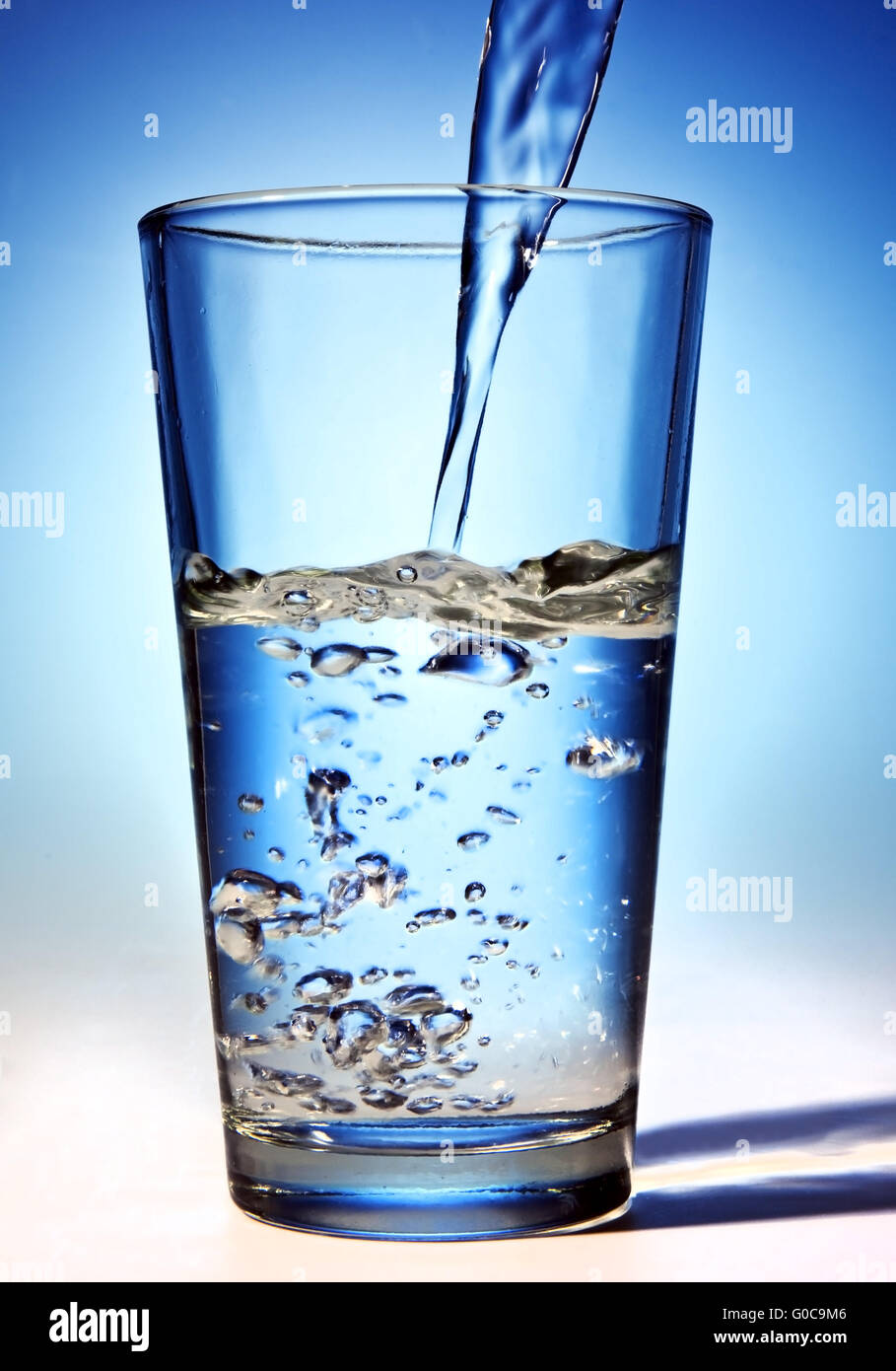 L'acqua viene versata in un bicchiere Foto Stock