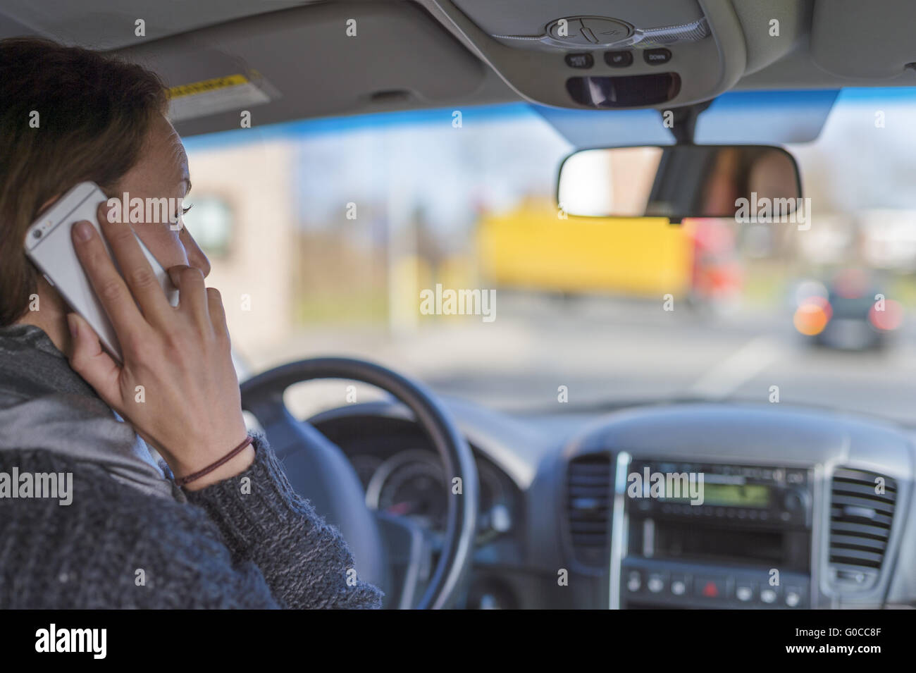 Giovane donna seduta al volante di una vettura e phon Foto Stock