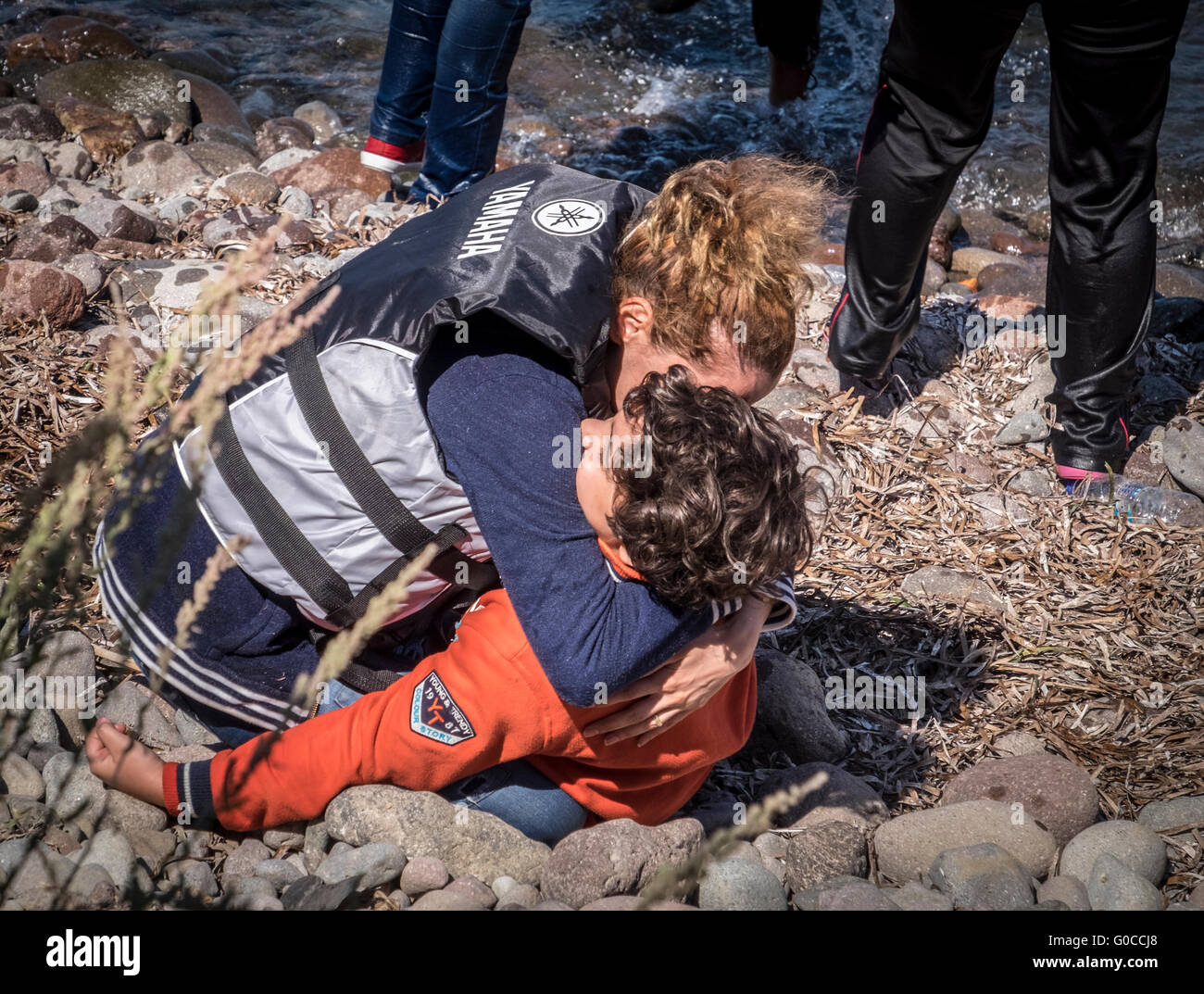 Rifugiato siriano madre abbraccia il suo giovane figlio come si arriva tranquillamente in Lesvos, Grecia dopo la traversata del mare Egeo dalla Turchia Foto Stock