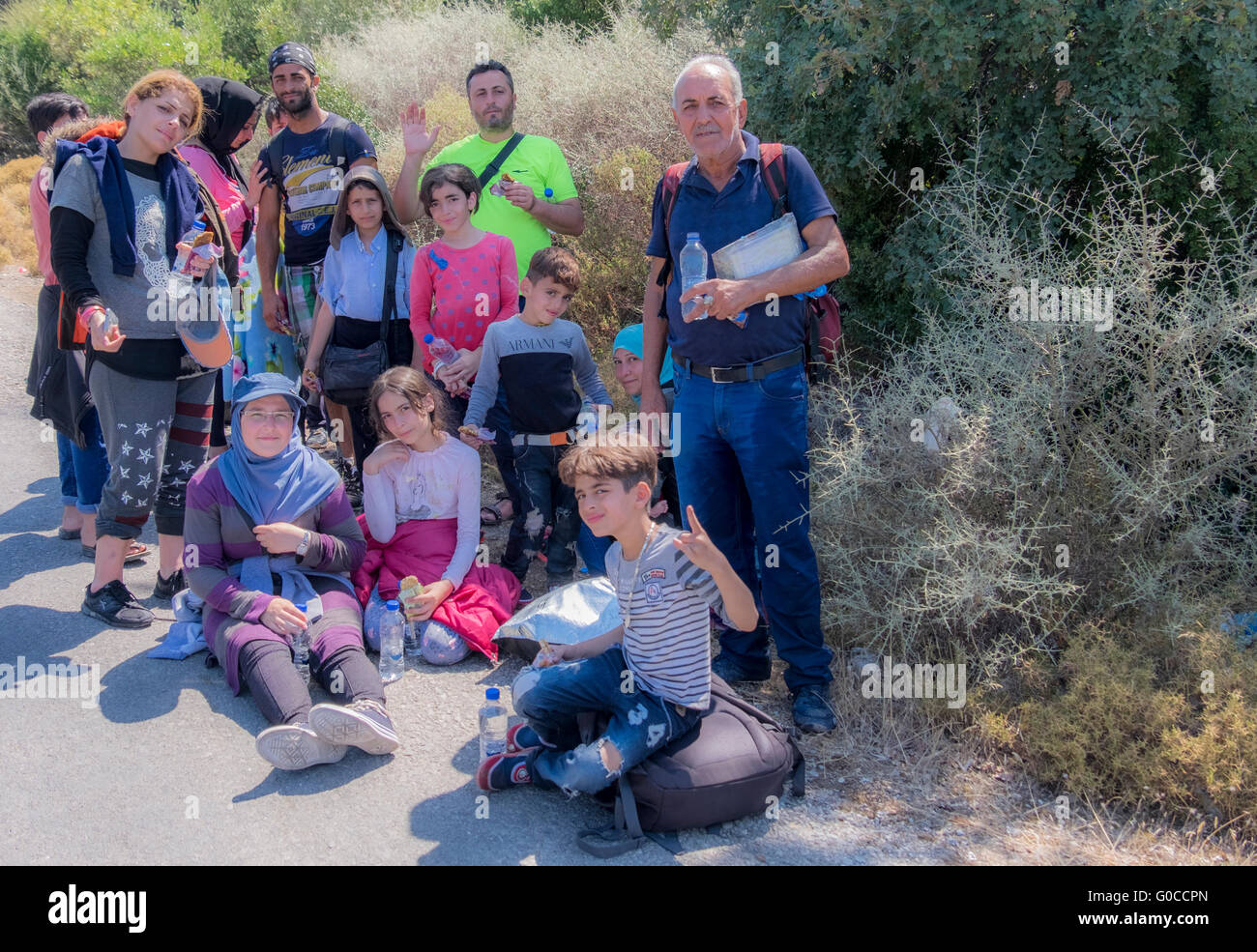 Famiglia di profughi siriano inizia il lungo cammino verso la capitale dell'isola dopo lo sbarco in zattere sulla costa settentrionale di Lesbo. Foto Stock