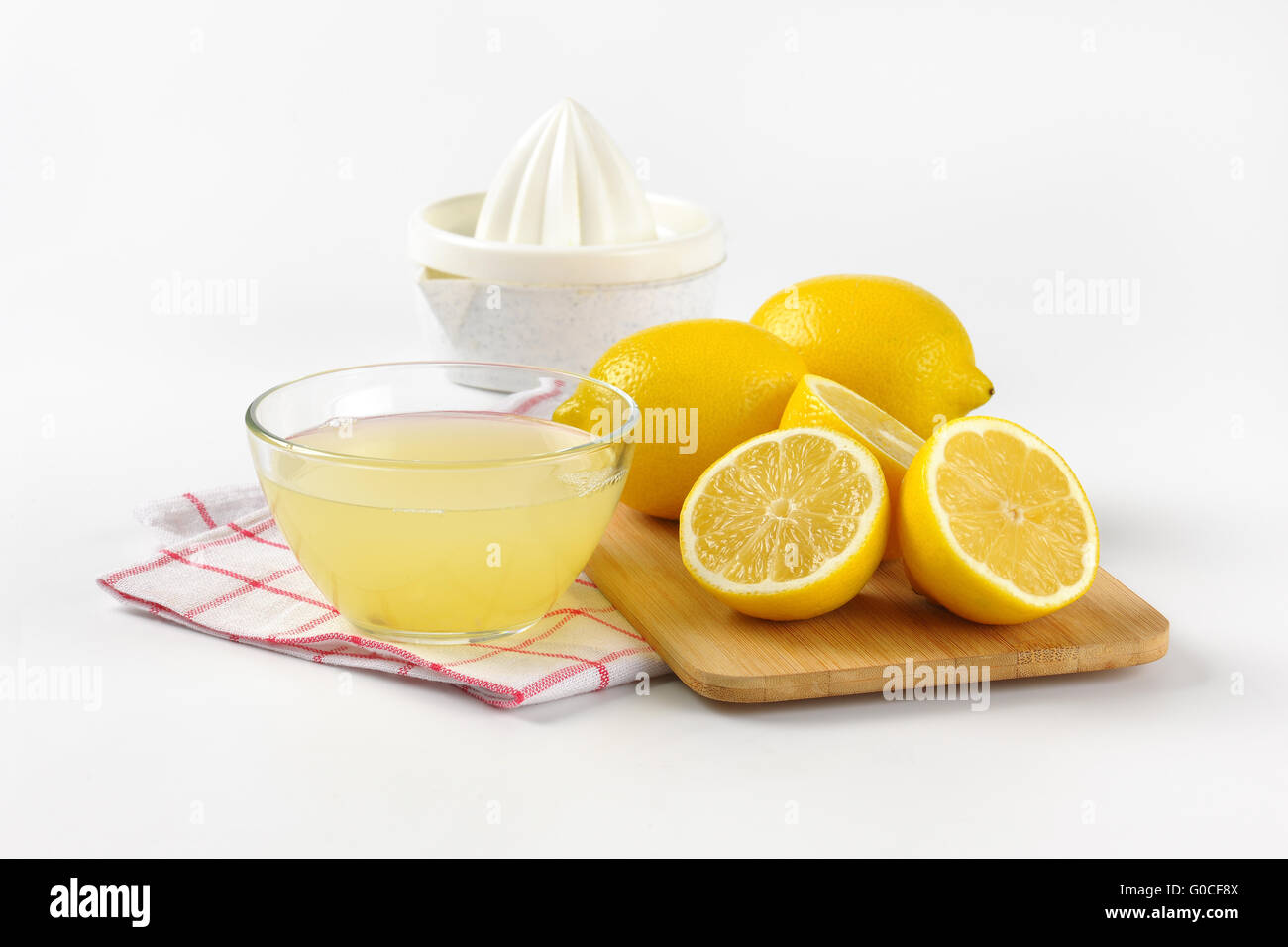 Ciotola di spremuta di limone, il succo di limone e spremitore maturo limoni sul tagliere di legno Foto Stock