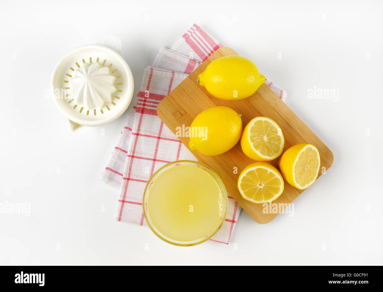 Ciotola di spremuta di limone, il succo di limone e spremitore maturo limoni sul tagliere di legno Foto Stock