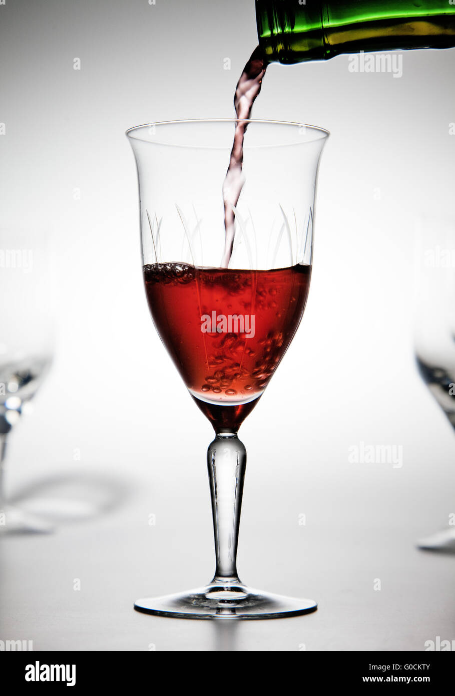 Il vino rosso è versata in un bicchiere da vino Foto Stock