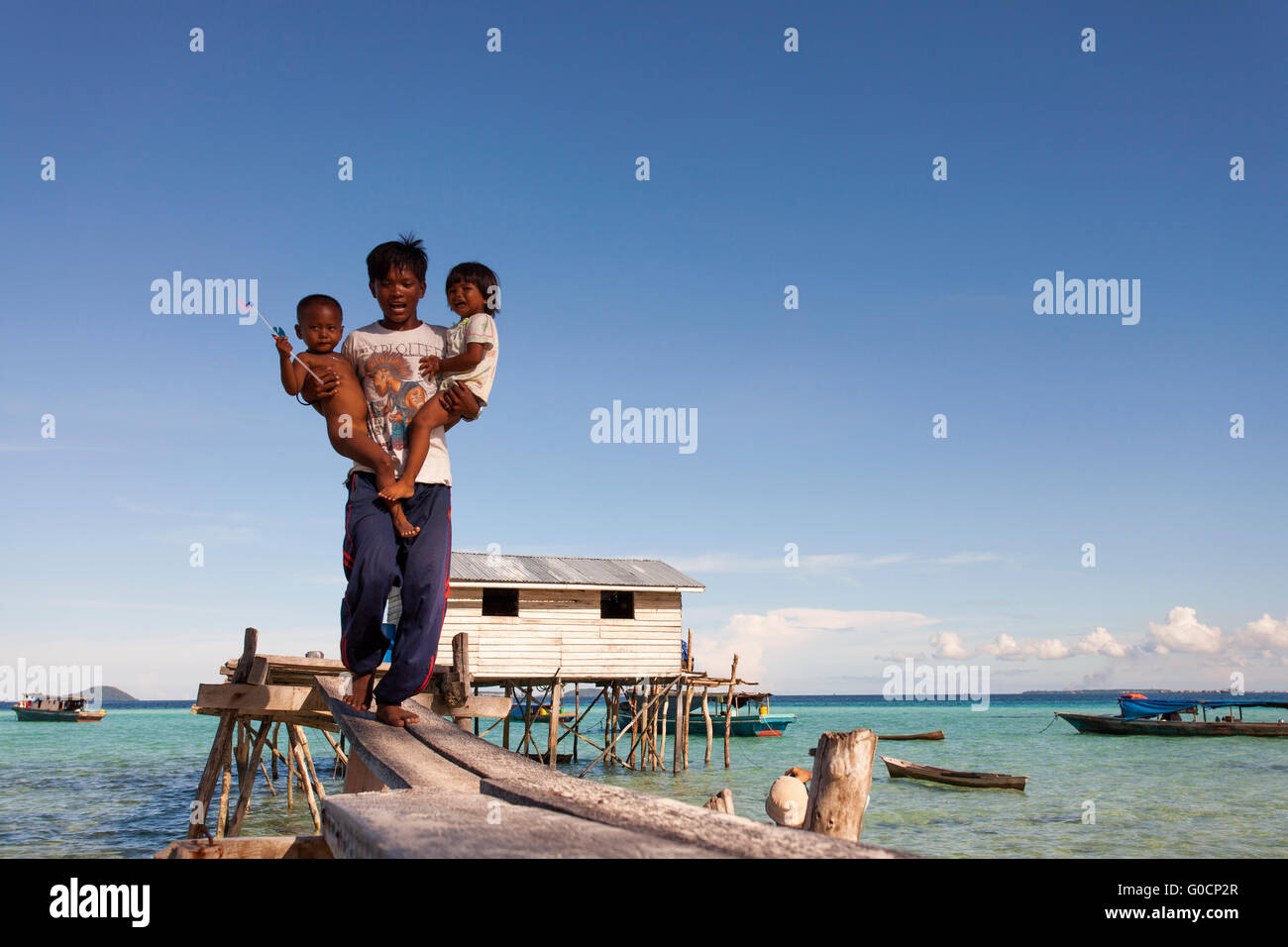 Ritratto di giovane non identificato padre bajau locali etnici suluk con il suo bambino pongono per la telecamera in Sibuan. Foto Stock